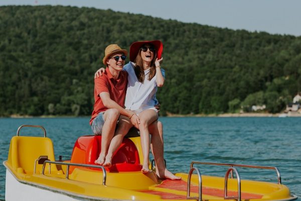 Couple in love laughing while boating in the lake. Portrait of young man and woman having fun pedal boating.